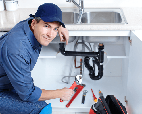 plumber smiling working on kitchen sink